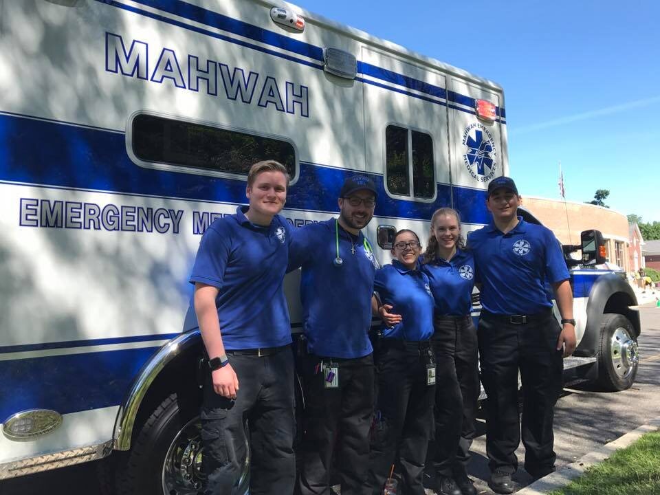 Mahwah EMS members posing together in front of an ambulance on a sunny day