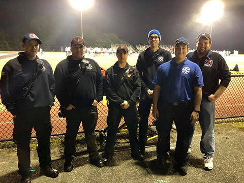 Mahwah EMS members standing by at a high school football game at night